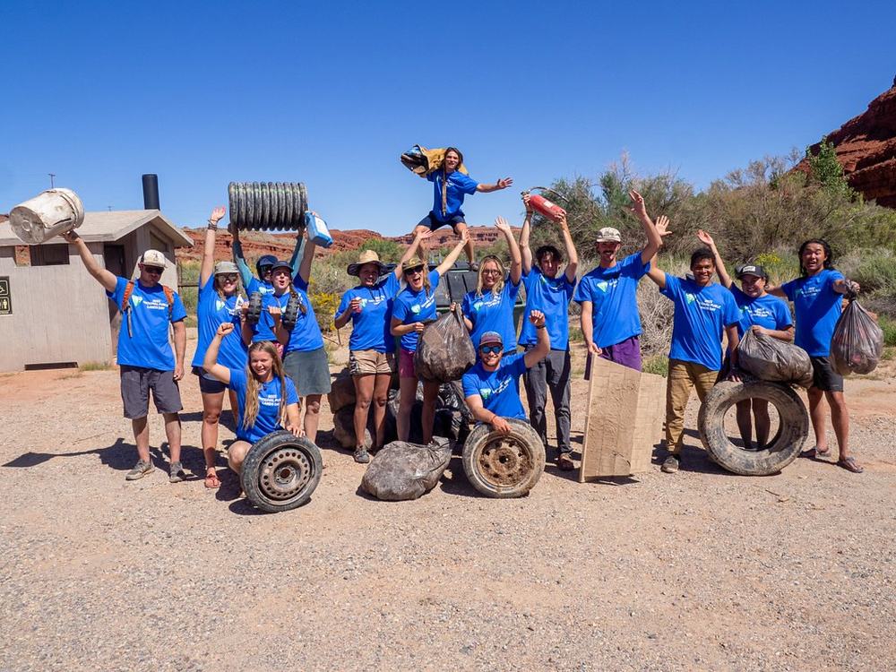 A crew of young volunteers cheers behind the tyres and scrap it cleared from a river bank.